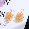 Close-up of golden tassel earrings with translucent yellow natural crystal stones - Gold Hook Style / Yellow Chip Stone