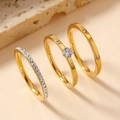 Detalle macro de un juego de tres anillos de acero inoxidable dorado con circones - US 6 / Dorado