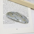 Elegante fermaglio per capelli ovale in acetato marmorizzato su sfondo di un libro - Marmo Grigio