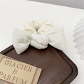 Detail of a white satin bow scrunchie with silky finish on a wooden tray decor - White Bowknot
