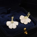 Elegant cream flower earrings with golden core on a navy blue velvet jewelry box background - Cream Gold Flower Leverback Earrings