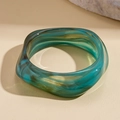 Close-up of marble pattern acrylic resin bangle with emerald green and brown fluid textures - Blue
