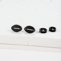 Macro view of matte black football earrings showing fine stitching texture and secure backings - Rugby Ball / Black