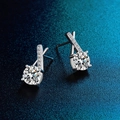 Close-up of D color moissanite earrings in 925 silver on deep blue textured backdrop - Criss Cross Studs
