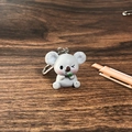 Primer plano de un lindo llavero de koala gris de resina sobre un fondo de madera oscura - Koala con hoja / Gris