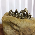 Makroaufnahme von Bronze-Briefbeschwerer in Gebirgsform auf einem Natursteinsockel - Berg Briefbeschwerer / Bronzegold
