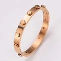 Elegante brazalete de acero inoxidable en oro rosa con remaches industriales y acabado cepillado - Oro rosa