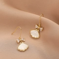 Elegant gold bow earrings with white shell pendants on silk background - Gold E246 Bow Shell
