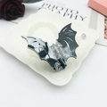 Detail of bat-shaped acetate hair claw clip with dark marble texture on vintage tray - Black White Ink Texture