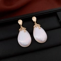 Elegant gold drop earrings featuring white iridescent ribbed pearls on a black display - Gold White Iridescent Teardrop