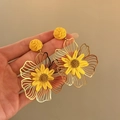 Detailopname van handgemaakte gele raffia en goudkleurige metalen bloem oorbellen - Geel