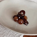 Détail d'une petite pince à cheveux ambre avec perles posée sur un plat en céramique - Mini Pince Style Maillard / Ambre