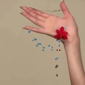 Dettaglio della collana a fiori con petali rossi e perline blu su una catena in metallo - Collana di Perline con Fiori Dopamina / Blu e Rosso