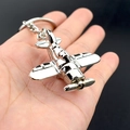 Sleek silver fighter jet metal keychain held against a minimalist black background - Silver Propeller Plane