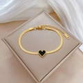 Primer plano de pulsera de cadena de serpiente dorada con dije de corazón negro y S.STEEL - Dorado