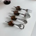 Juego de cubiertos de 4 piezas en acero inoxidable con mangos de caracol marino - Cuchara de ojo de gato marrón verde