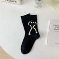 Schwarze Baumwollsocken mit weißen Herz-Fransen-Bändern auf einem sauberen weißen Tisch - Einheitsgröße / Schwarz Seilgebundenes Herz