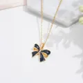 Elegante collar dorado con colgante de lazo y circonitas sobre mármol blanco - Lazo Oro Negro