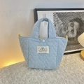 Light blue quilted handbag with heart pattern and HAPPY patch on plush white rug - Mini / Light Blue