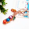 Golden pea pod keychain featuring colorful cat eye stones and a small rhinestone peanut - Colorful Rhinestone Peanut
