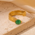 Detailansicht eines goldenen Federrings mit grünem Katzenaugenstein auf Steindekor - Grüner Stein Feder Stil (TYR0770)