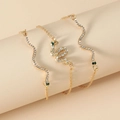 Detail of gold snake bracelets with white zircon pave and green stone eyes on a prop - KC Gold Snake Collection (2367)