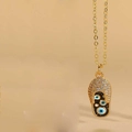 Détail macro du pendentif tong en or avec zircons incrustés et motifs œil de protection - Mauvais Oeil Noir