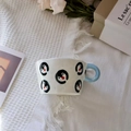 Top view of hand-painted ceramic mug with blue handle on a white tassel fabric - Penguin