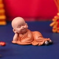 Smiling little monk figurine in orange robe lying on side for car interior decor - 1034-22 Side Lying Smile