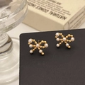 Macro detail of elegant gold bow earrings with white pearls on a black jewelry stand - Gold Bow Pearl Stud Earrings