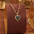 Macro shot of an emerald heart pendant with white diamonds on a gold rope chain necklace - Green