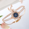 Reloj elegante de oro rosa con esfera floral y pulsera de perlas sobre espejo - Azul