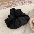 Detail of a large black satin scrunchie with a fluffy texture on a cream textile background - Black