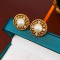 Vintage gold pearl earrings with sparkling crystals on a textured jewelry box background - Gold