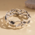 Detail eines silbernen, S-förmig gewundenen Gliederarmbands mit schwarzem Vintage-Finish - Silber