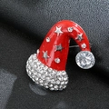 Macro shot of red enamel Christmas hat brooch with glittering pavé crystals on black leather - Silver Christmas Hat