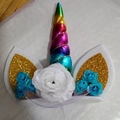 Detail van regenboog eenhoorn taarttopper met gouden pailletten oren en witte bloemen - Regenboog