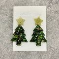 Glitzernde grüne Acryl-Weihnachtsbaum-Ohrringe mit goldenen Sternen auf grauem Steinboden - Grüner Glitzer Weihnachtsbaum