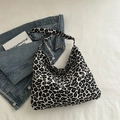 Elegante borsa tote in tela con stampa leopardata bianca e nera appoggiata sul letto - Nero