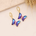 Close-up of 18K gold butterfly earrings with blue gradient crystals and white diamonds - Dark Purple