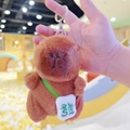 Brown capybara plush keychain with green crossbody bag and white embroidery detail - Dark Brown Green Fortune + Silver Clip