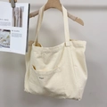 Close-up of cream canvas tote bag showing the front pocket and fabric texture - Off White