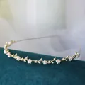 Dettaglio di un cerchietto dorato con fiori di perle bianche e design a vite su velluto - Piccolo Fiore Di Perla