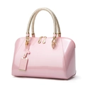 Pink patent leather Boston handbag with gold hardware and woven handles on white background - Pink