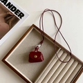 Macro shot of a red leather mini handbag pendant necklace on a wooden jewelry tray - Wine Red Leather Bag Style