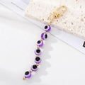 Macro detail of purple resin evil eye beads on a golden keychain with lobster clasp hook - Purple