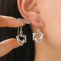 Detailed close-up of silver sea dolphin drop earrings featuring a circular hollow design - Jumping Dolphin Style (5556) / Antique Silver