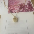 Golden heart pendant necklace with shimmering crystals on a decorative gift card - Letter V