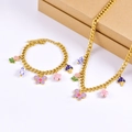 Detail of gold chain set with porcelain beads, enamel butterfly, and floral charms - Necklace + Bracelet