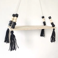 Detail of wooden wall shelf with black geometric beads and cotton tassels - Black